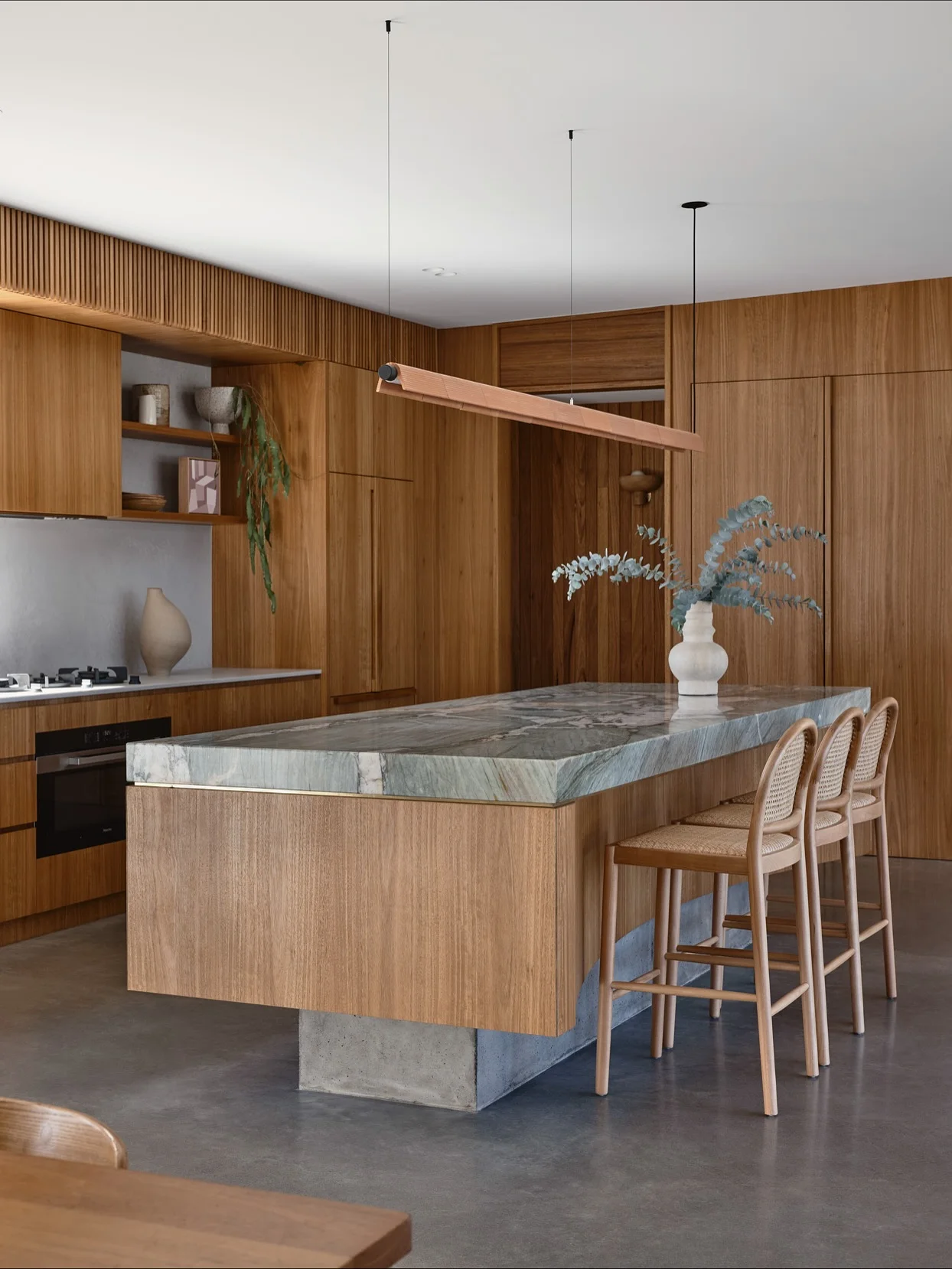 Green marble island and shelves in a timber kitchen