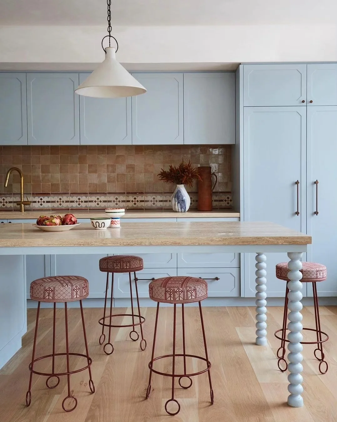 Travertine benchtop with a 40mm mitred edge in a pale blue kitchen