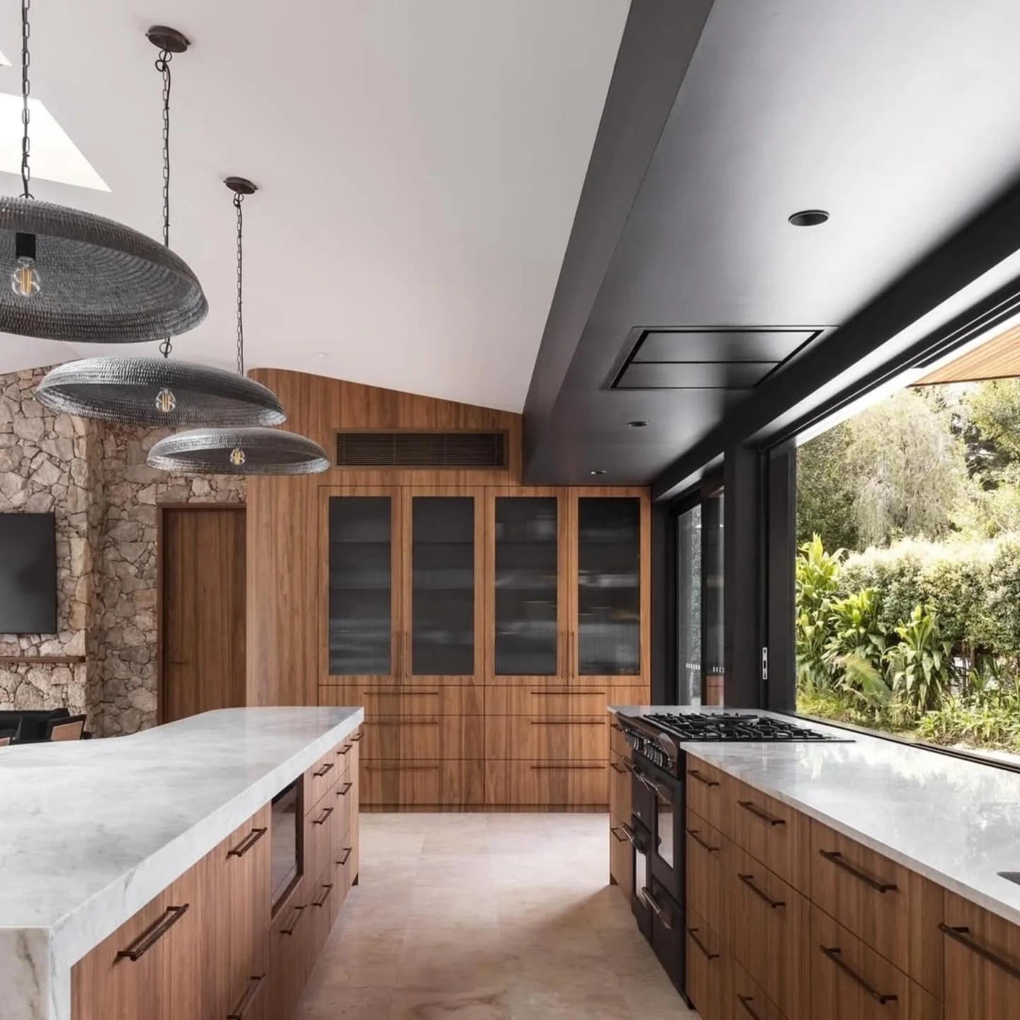 Taj Mahal quartzite benchtop and stone feature wall under black pendant lights