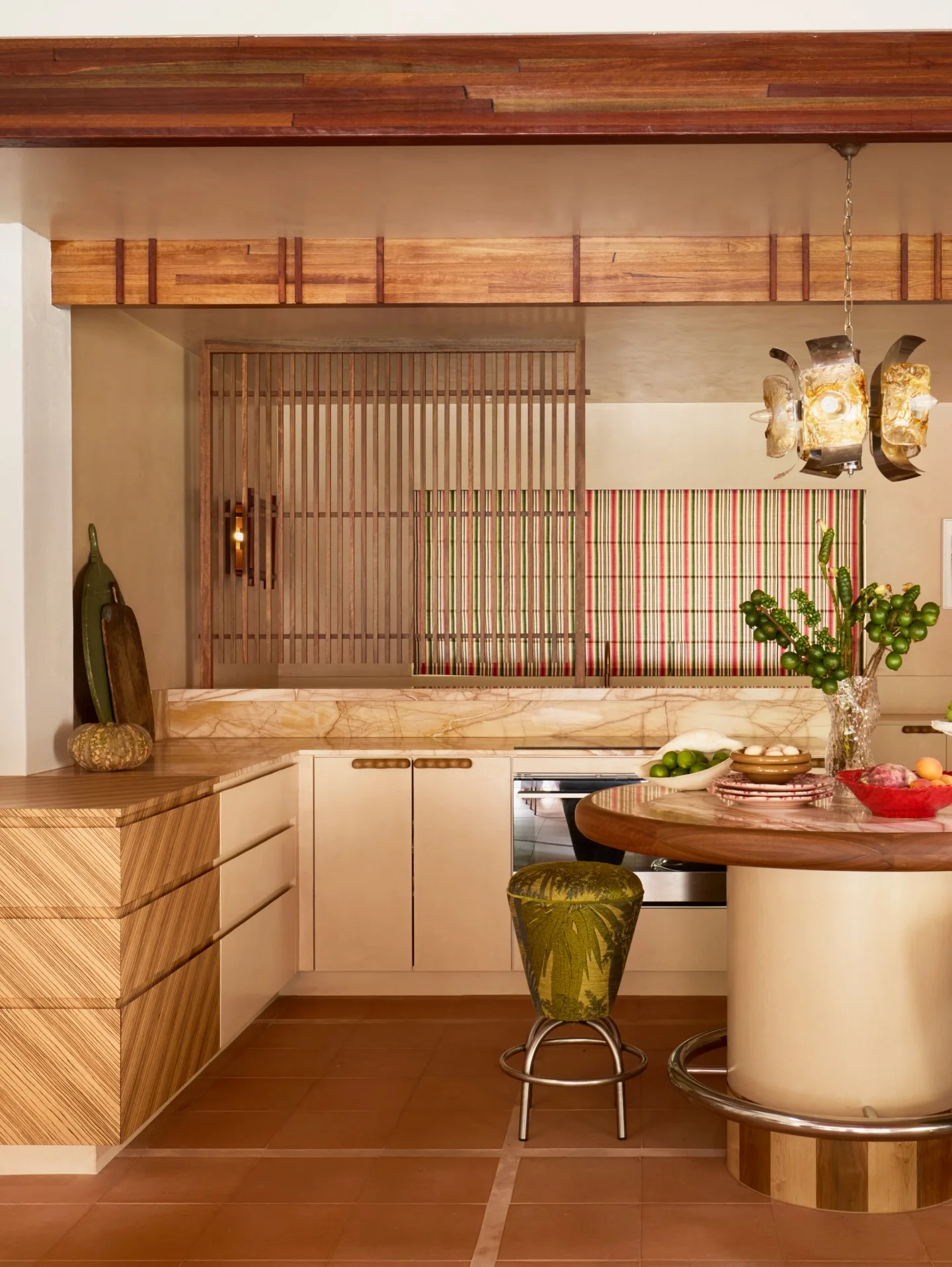 Red veined stone splashback and benchtop with timber cabinetry and a brass tap