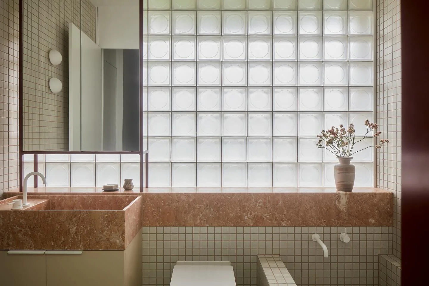 Red stone vanity beside a glass block wall