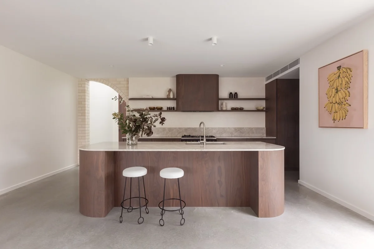 Curved walnut island with a Taj Mahal quartzite top and two stools