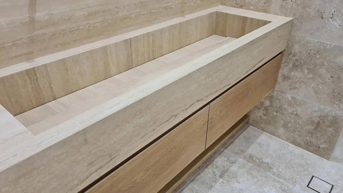 Travertine vanity with a hand carved integrated basin above oak drawers
